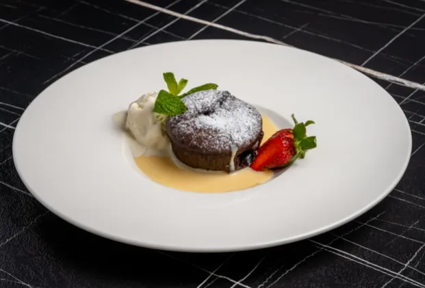 Warm chocolate pudding with red currants and ice cream