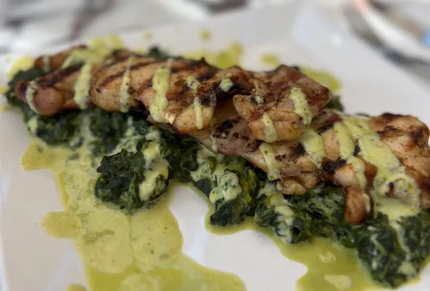 Grilled chicken thigh on a bed of spinach