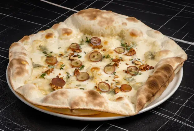 Four-cheese pizza with walnuts and black grapes